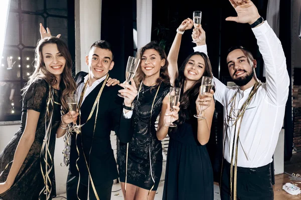 Chicas y chicos vestidos con ropa elegante y elegante divertirse y beber copas con champán en el estudio. Tiempo de fiesta — Foto de Stock