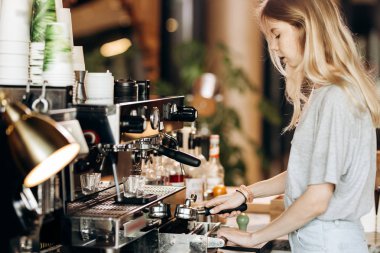 Çok ince sarışın genç gündelik kıyafeti giymiş popüler bir kafede kahve pişirme.