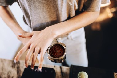 Gündelik kıyafeti giymiş bir genç oldukça ince kız modern bir kafede kahve pişiriyor. Bu süreci üzerinde duruluyor.