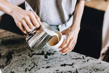 Gündelik kıyafeti giymiş bir genç ince nazik sarışın kız, ustaca modern bir kafede kahve süt ekler.