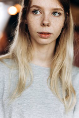 Rahat tarzı, giyen sevimli ince güzel kız, bir yere dikkatle modern bir kafede görünüyor.