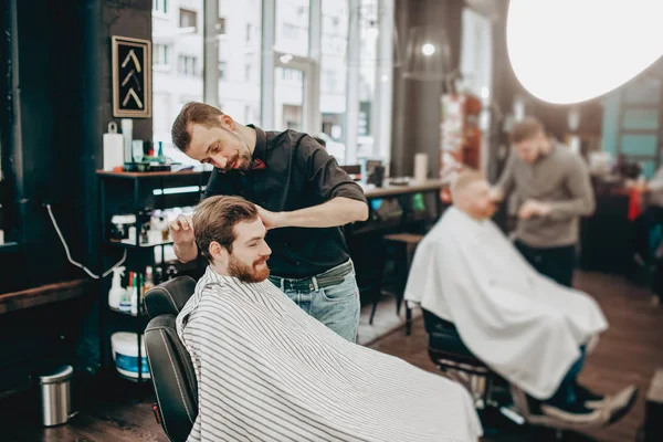 Barbers make a stylish hairstyles to men in a barbershop