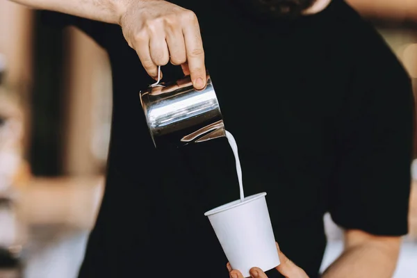 Barista carefully pours the milk into a glass in a modern coffee shop. — Stock Photo, Image