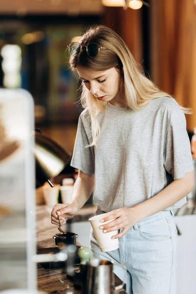 Przystojny Szczupła blondynka z długimi włosami, ubrany w strój casual, gotowania kawy w nowoczesną kawiarnię. Przedstawiono proces parzenia kawy. — Zdjęcie stockowe