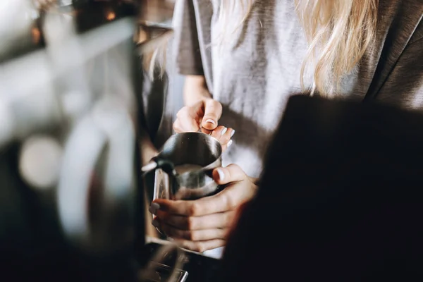 Молода гарненька дівчинка, одягнена в повсякденне вбрання, готує каву в сучасному кафе. Вона фокусується на процесі . — стокове фото