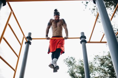 Siyah tayt ve dışında spor çubuğunda yükselişte zemin kırmızı şort yapar kafa bandı çıplak gövde ile atletik adam giymiş