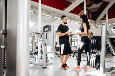 Spor salonunda spor hocası ile siyah spor top ve onun boyun görüşmeler havluda tayt giymiş esmer atletik kız
