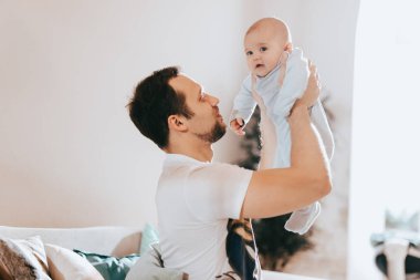 Işık odasında kanepede onun küçük güneşi genç baba tutar