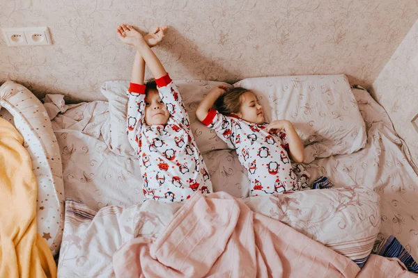 Δύο μικρότερες αδελφές ντυμένος με πιτζάμες στον ύπνο στο κρεβάτι στην κρεβατοκάμαρα — Φωτογραφία Αρχείου