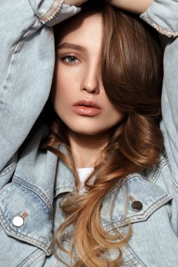 Uzun akan saçlı Kot ceket pozlar başında stüdyoda koyu arka plan üzerinde ellerini tutarak giymiş genç esmer kız