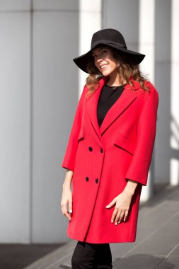 Esmer kız sevimli parlak kırmızı ceket ve şık şapka ile geniş ağzına kadar pozlar sokakta giymiş