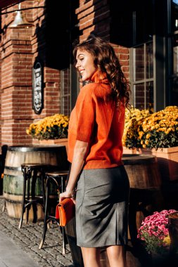 Gri etek giymiş şık ince kız portakal bluz turuncu küçük ihale sokakta güneşli bir günde yürür