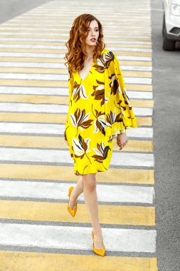 Güzel kadınlar şık yaz sarı kahverengi çiçekli elbise sıcak bir günde sokak bir şehirde yürüyüş giyinmiş