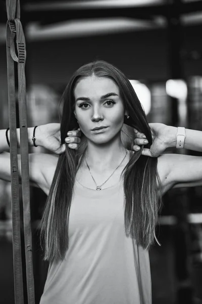 Чорно-біле фото красивої спортивної дівчини, одягненої у спортивний одяг, що стоїть у спортзалі з руками на волоссі — стокове фото