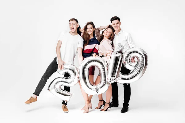 Šťastný, že dvě holčičky a dva kluci oblečený v stylové oblečení drží balónky ve tvaru čísla 2019 na bílém pozadí v ateliéru — Stock fotografie