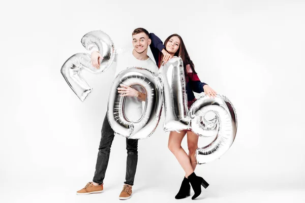 Chica divertida y chico vestido con una ropa elegante con estilo están sosteniendo globos en forma de números 2019 sobre un fondo blanco en el estudio — Foto de Stock