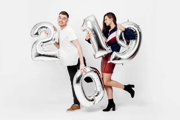 Αστείο κορίτσι και άντρας ντυμένος με ένα κομψό έξυπνο ρούχα κρατούν μπαλόνια με τη μορφή των αριθμών 2019 σε λευκό φόντο στο στούντιο — Φωτογραφία Αρχείου