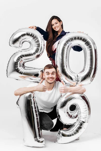 Κοπέλα και άντρας ντυμένος με ένα κομψό ρούχα τη διασκέδαση με μπαλόνια με τη μορφή των αριθμών 2019 σε λευκό φόντο στο στούντιο — Φωτογραφία Αρχείου