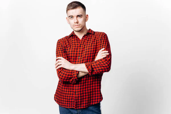 Le gars vêtu de chemise à carreaux rouges et de jeans se tient sur le fond blanc dans le studio — Photo