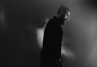 Profil sis siyah ve beyaz fotoğraf siyah gömlek giymiş bir sakal ile şık bir adam duruyor
