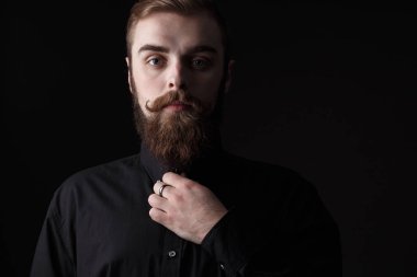 Sepya siyah arka plan üzerine siyah gömlek giymiş şık saç ve sakal ile şık bir adam portresi