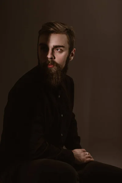 Sepia foto retrato de un hombre pensativo con una barba vestida con la camisa negra sobre el fondo blanco — Foto de Stock
