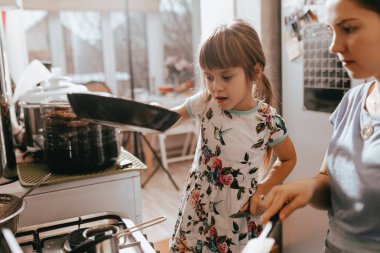Küçük kız annesi krep yemek kahvaltı için küçük rahat mutfakta yardımcı olur.