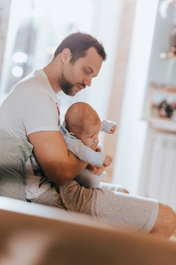 Genç Baba onun kollarında onun küçük güneş ışık odasında kanepede tutar.