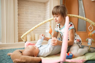 Küçük kardeşi halı odasında yerde yatan küçük sevimli kız bakar