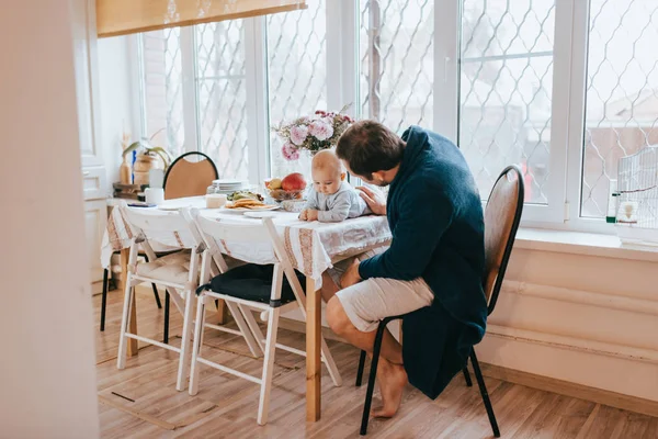 Père s'assied sur une chaise et regarde son petit fils allongé sur la ta — Photo