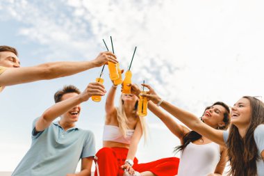 Gülüyor ve Nehri yanındaki güzel kafede sarı kokteyl içme yakışıklı arkadaş şirket. Şerefe. Eğlence, iyi vakit geçiriyor. Arka planda nehirdir.