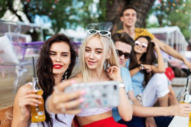 Sosyalleşme ve güzel yaz kafede masada selfie yapma gülüyor ve sarı kokteyller, içme yakışıklı arkadaş şirket. Şerefe. Eğlence, iyi vakit geçiriyor. Dostluk.