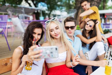 Sosyalleşme ve güzel yaz kafede masada selfie yapma gülüyor ve sarı kokteyller, içme yakışıklı arkadaş şirket. Şerefe. Eğlence, iyi vakit geçiriyor. Dostluk.