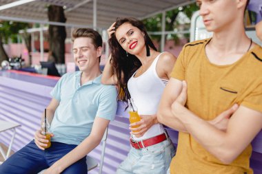 Gülüyor, sarı kokteyl içme ve güzel yaz kafe barda sosyalleşme yakışıklı arkadaş şirket. Şerefe. Eğlence, iyi vakit geçiriyor. Dostluk.