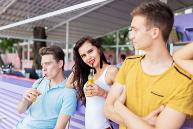 Gülüyor, sarı kokteyl içme ve güzel yaz kafe barda sosyalleşme yakışıklı arkadaş şirket. Şerefe. Eğlence, iyi vakit geçiriyor. Dostluk.