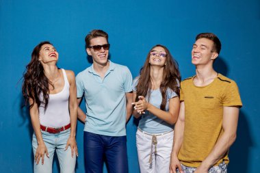 Dört yakışıklı arkadaş mavi duvar önünde dururken gülüyorlar. Eğlence, iyi vakit geçiriyor. Dostluk, ilişki.