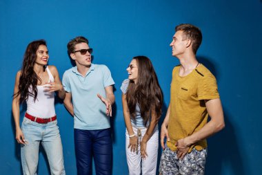 Dört yakışıklı arkadaş mavi duvar önünde dururken gülüyorlar. Eğlence, iyi vakit geçiriyor. Dostluk, ilişki.