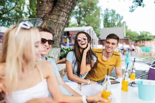 Μια παρέα φίλων όμορφος γελώντας και πίνοντας κοκτέιλ κίτρινο και κοινωνικοποίηση στο τραπέζι στην καφετέρια ωραίο καλοκαίρι. Γεια. Ψυχαγωγία, έχοντας καλή στιγμή. Φιλία. — Φωτογραφία Αρχείου