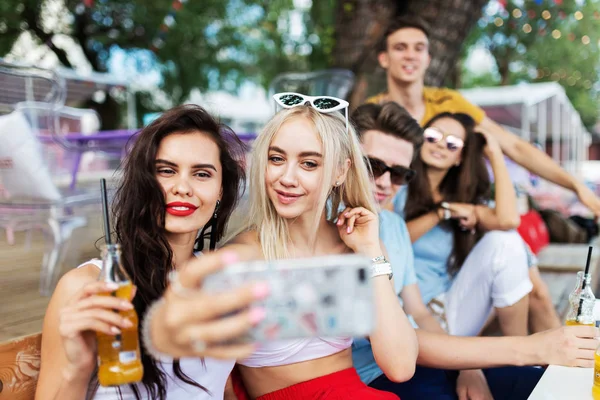 A cég csinos meg nevetett, és sárga koktélozás, társasági, és így selfie a szép nyári Café asztalánál. Üdv. Szórakozás, a jó idő. Barátság. — Stock Fotó