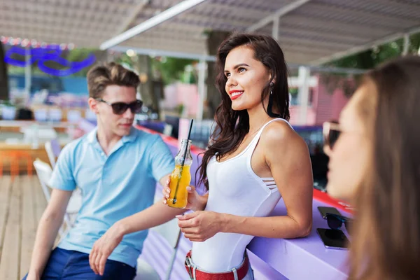 Gülüyor, sarı kokteyl içme ve güzel yaz kafe barda sosyalleşme yakışıklı arkadaş şirket. Şerefe. Eğlence, iyi vakit geçiriyor. Dostluk.