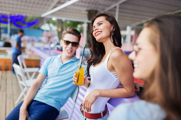 Une compagnie de beaux amis riant, buvant des cocktails jaunes et socialisant au bar dans le joli café d'été. À la tienne. Divertissement, s'amuser. Amitié . — Photo