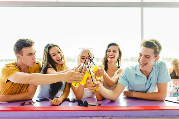 Μια παρέα φίλων όμορφος γελώντας και πίνοντας κοκτέιλ κίτρινο κοινωνικοποίηση στο μπαρ στο ωραίο καλοκαιρινό καφενείο. Ποταμός είναι στο παρασκήνιο. Γεια. Ψυχαγωγία, έχοντας καλή στιγμή — Φωτογραφία Αρχείου