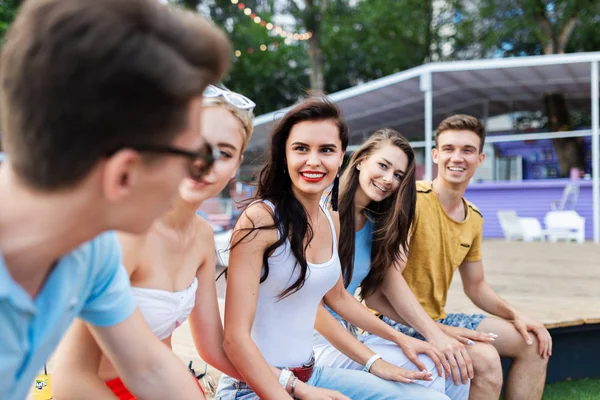 Eine Gesellschaft gut aussehender Freunde, die auf der Bank im netten Sommercafé lachten und gesellig zusammensaßen. Jubel. Unterhaltung, Spaß haben. Freundschaft. — Stockfoto