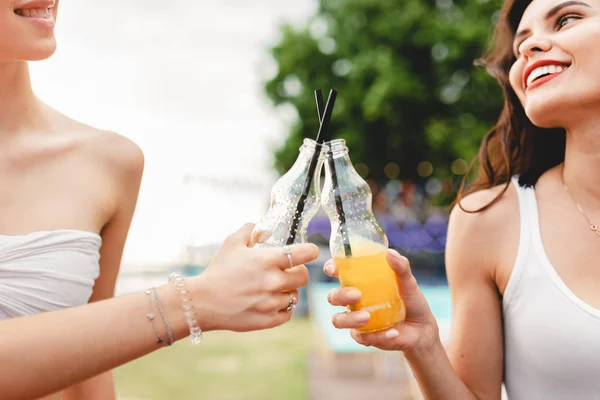 A company of good-looking friends laughing, drinking yellow cocktails and socialising in the nice summer cafe. Cheers. Entertainment, having good time. Friendship.