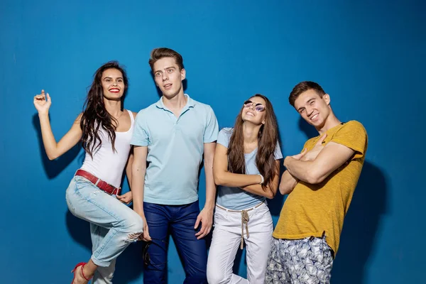 Dört yakışıklı arkadaş kendinden emin ve mutlu görünüyor sahip mavi duvar önünde dururken gülüyorlar. Eğlence, iyi vakit geçiriyor. Dostluk, ilişki.