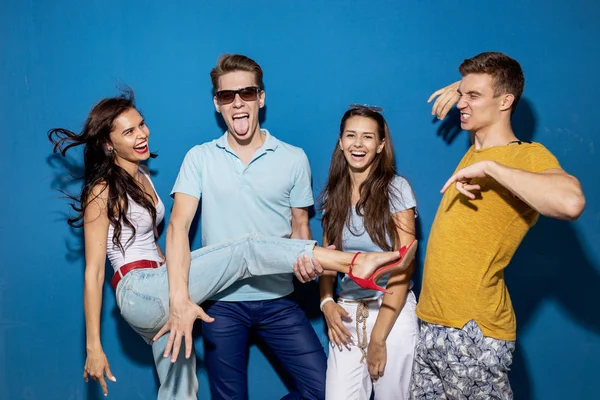 Dört yakışıklı arkadaş kendinden emin ve mutlu görünüyor sahip mavi duvar önünde dururken gülüyorlar. Eğlence, iyi vakit geçiriyor. Dostluk, ilişki.