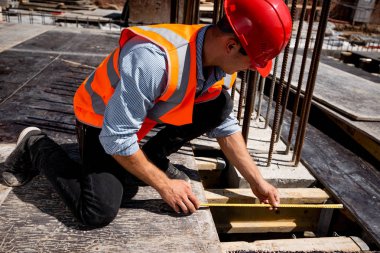Gömlek, turuncu iş yelek ve kask çalışmalarında bir mezura bina sitede delikle giyinmiş adam