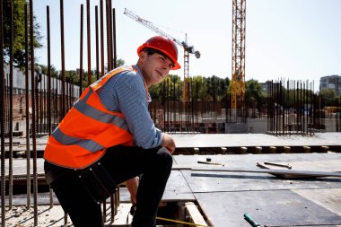Turuncu iş yelek ve kask giymiş Oluşturucusu bir dinlenme açık şantiyeye vardır.