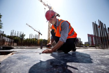 Turuncu iş yelek ve kask giymiş Oluşturucusu açık inşaat alanında bir çivi çekiç