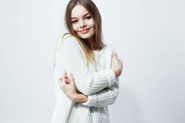 Stüdyoda beyaz zemin üzerine beyaz örgü kazak güzel uzun saçlı kız poz